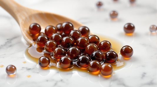Balsamic Caviar Pearls on a marble bench, being put there by a wooden spoon.