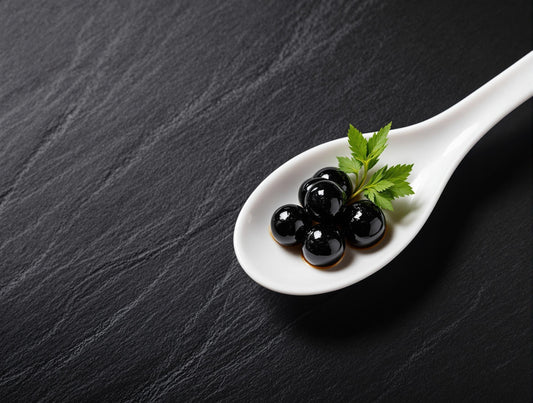 Sticky Balsamic Pearls on a white spoon with a green leaf garnish