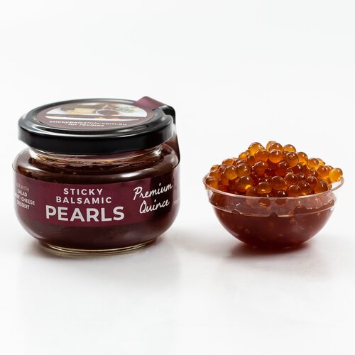 Sticky Balsamic Premium Quince jar next to a plastic container with quince pearls and a white background.