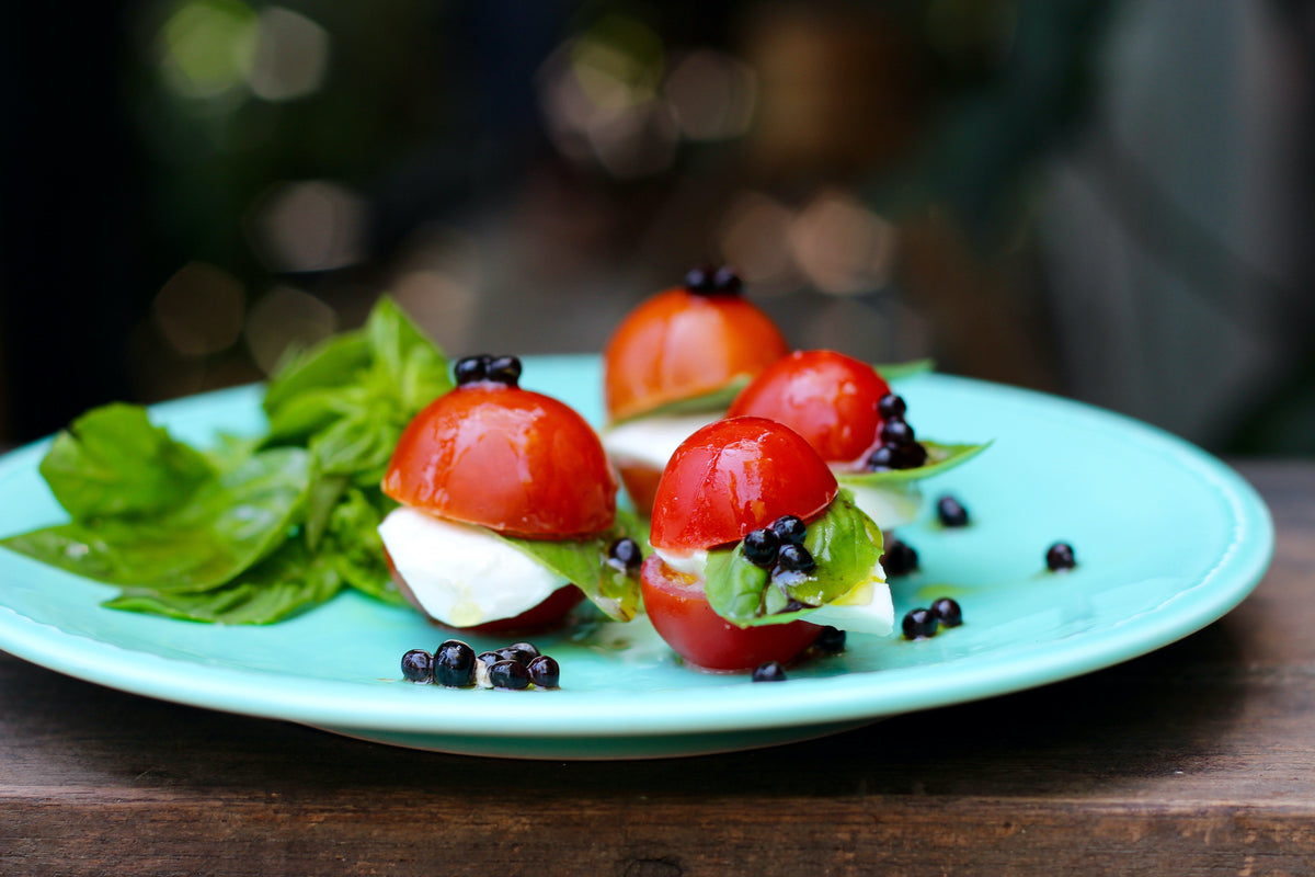 Sticky balsamic pearls gift topping on mozzarella, tomato, and basil leaves