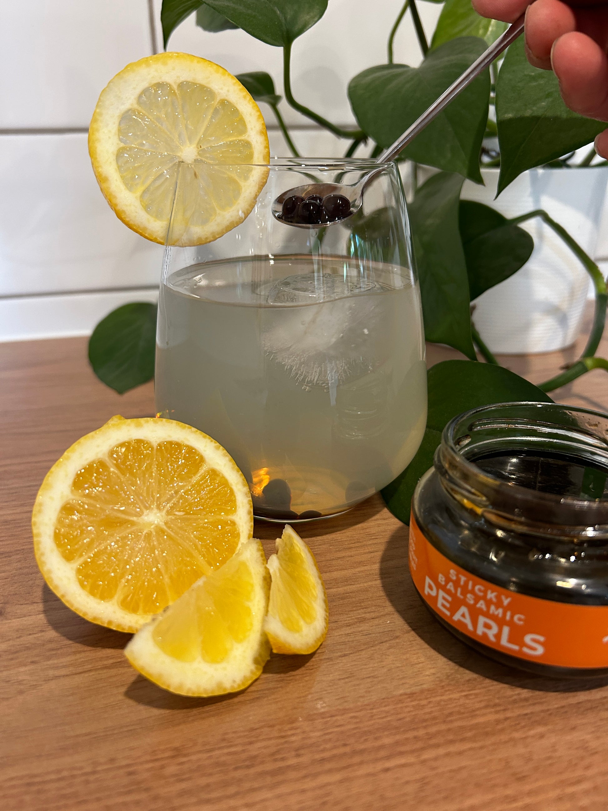 Balsamic pearls jar with dark pearls, lemons, and a pitcher drink