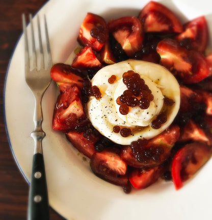 Sticky balsamic pearls on a plate with eggs, strawberries, and dark glaze