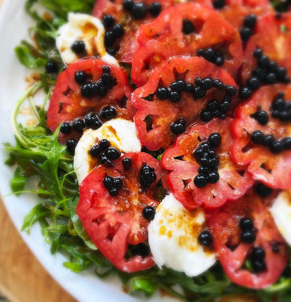Sticky balsamic pearls close-up on watermelon salad with basil and dark caviar