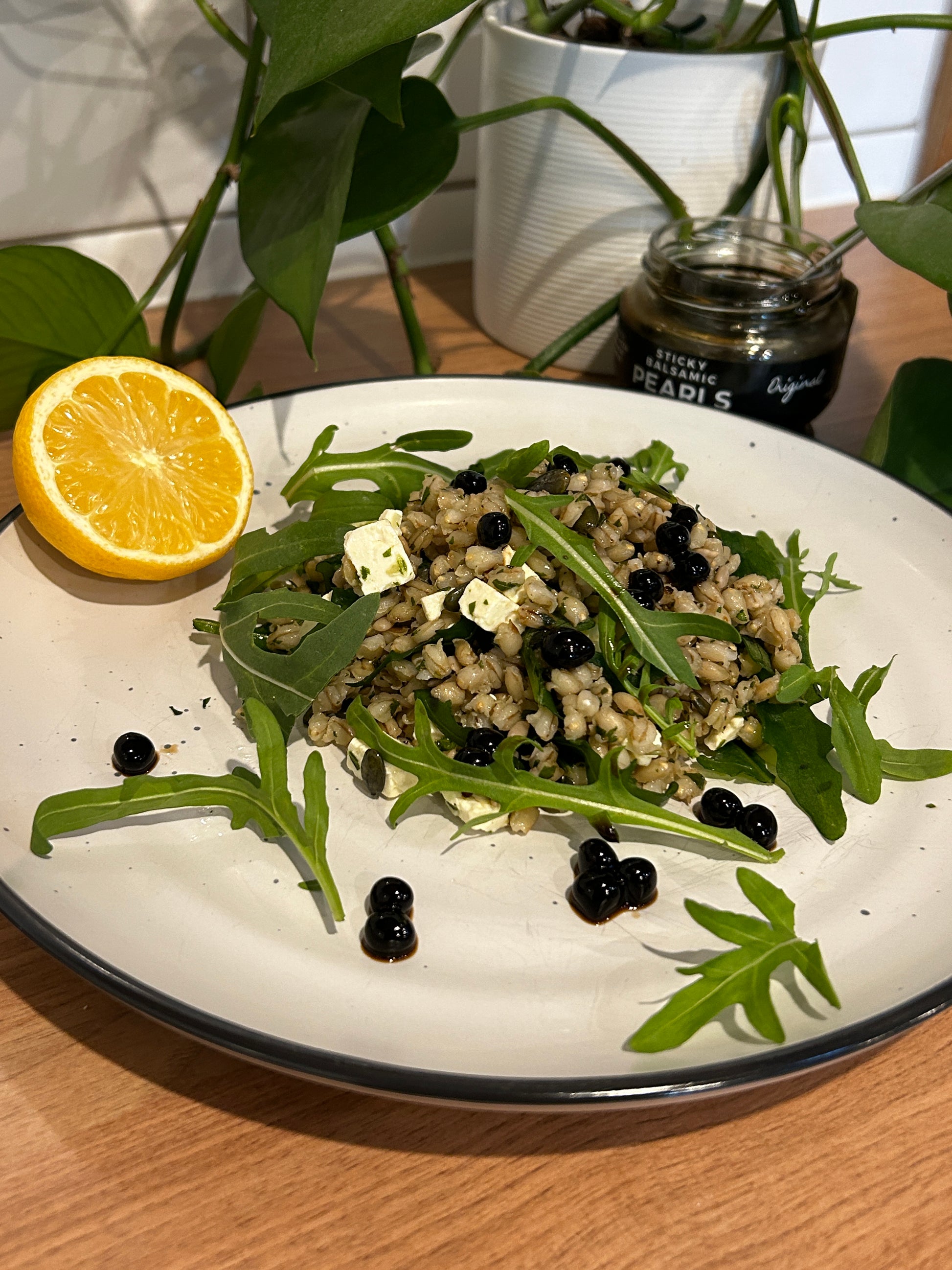 Sticky balsamic pearls over arugula salad on a white plate