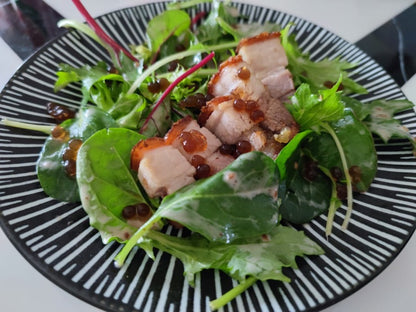 Green salad with sliced meat and dark balsamic pearls topping