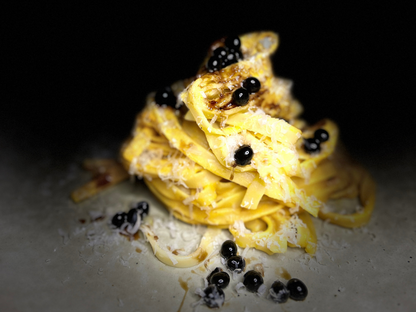 Sticky balsamic pearls on yellow pasta with dark sauce drops