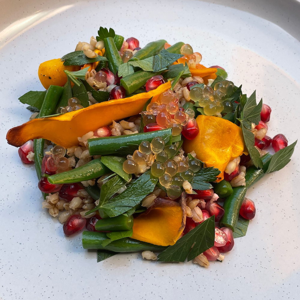 Sticky balsamic pearls topping mixed into salad with greens and pomegranate