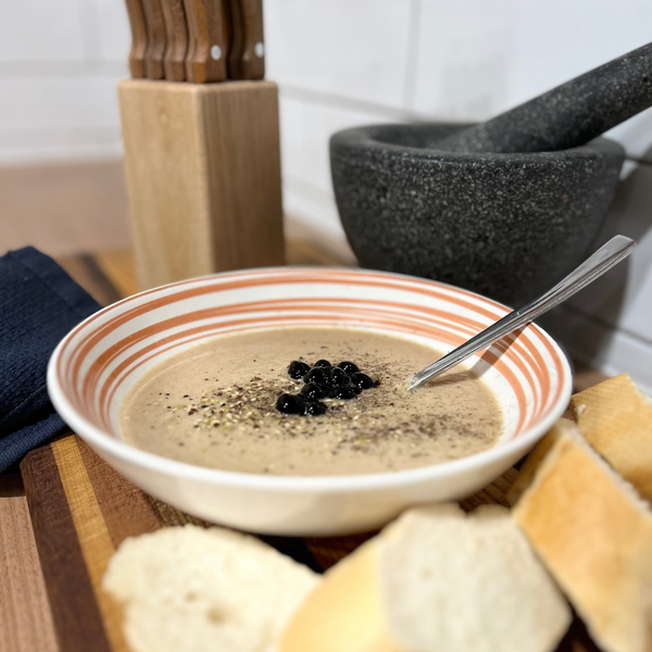 Cream soup in bowl with black balsamic pearls topping and bread