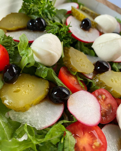 Fresh salad bowl with leafy greens, radish, tomatoes, and dark pearls