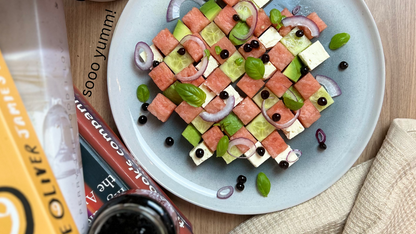 Sticky balsamic pearls topping on salad plate with watermelon cubes and greens