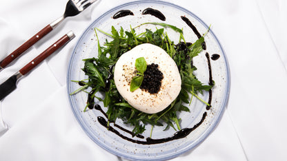 Sticky balsamic pearls on arugula salad with burrata and dark caviar dots