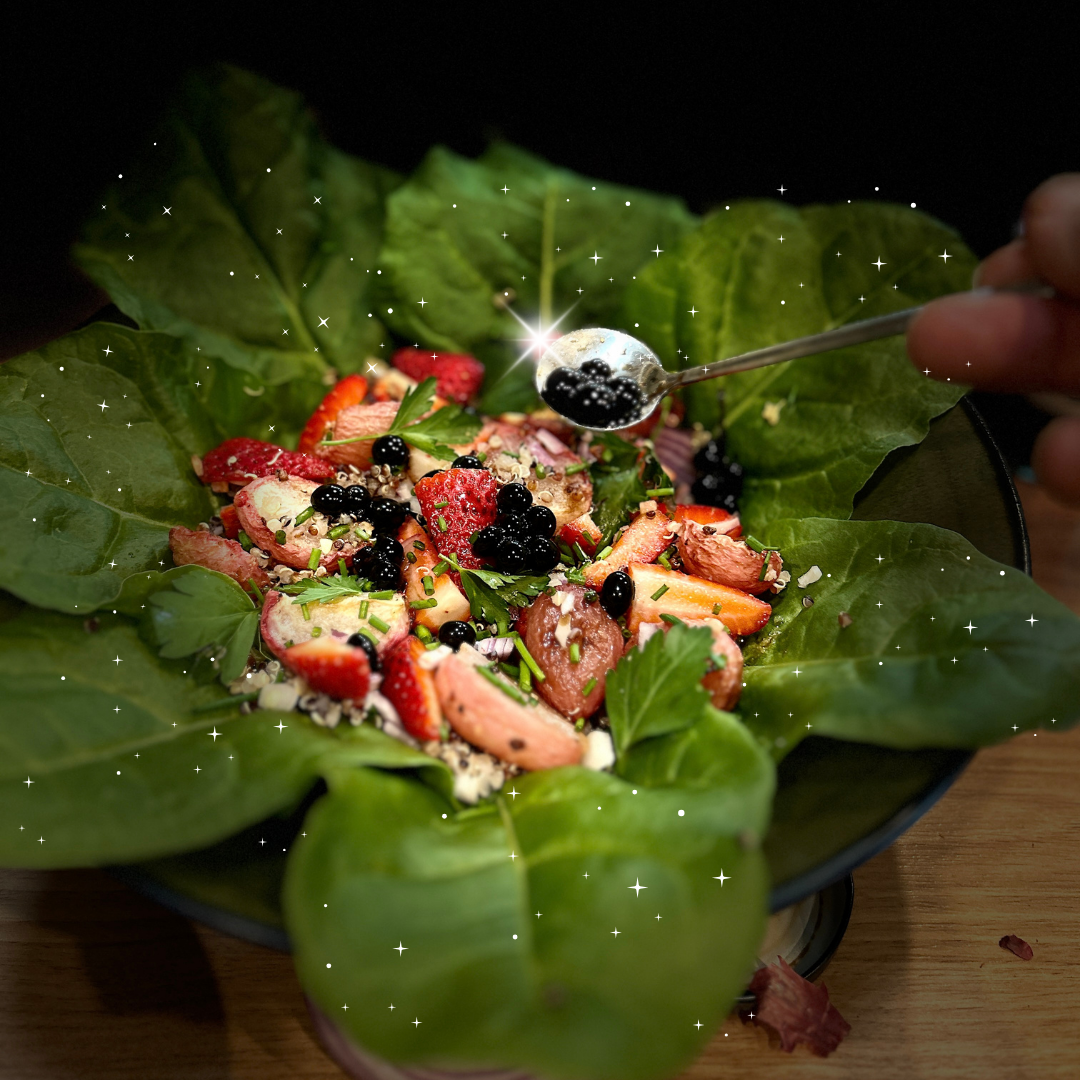 Sticky balsamic pearls spooned over a salad bowl with greens and strawberries