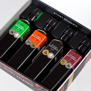 Balsamic bottle gift box with multiple dark bottles and labels in a black tray
