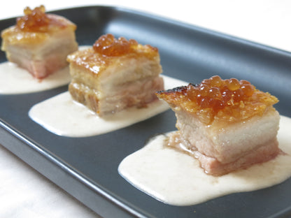 Pastry squares topped with dark balsamic pearls on a serving tray