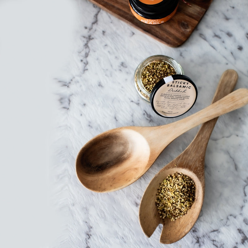Sticky balsamic dukkah spice in small jar with wooden spoons of nut-sesame mix