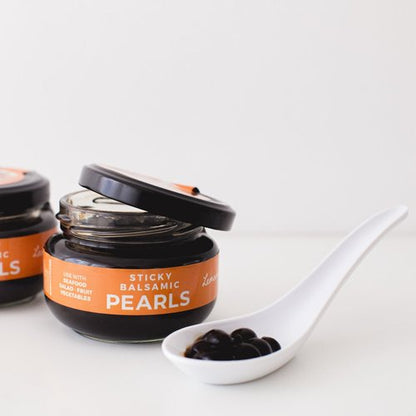 Balsamic pearls jars with black lids and spoon of dark pearls