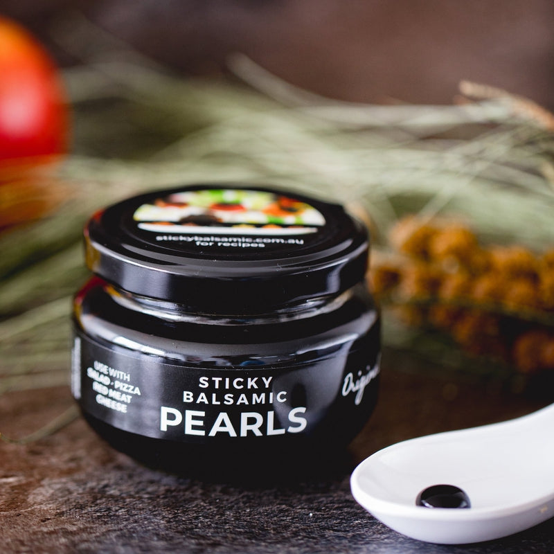 Sticky balsamic pearls jar with spoon of glossy black pearls on a countertop