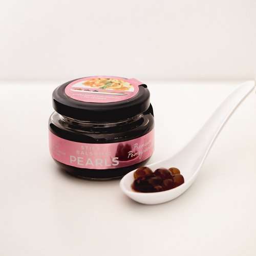 Sticky balsamic pearls jar with pink label and spoon of dark pearls