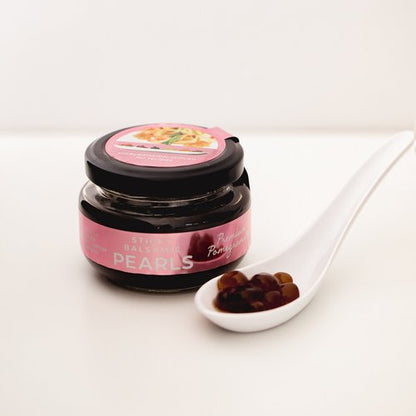 Sticky balsamic pearls jar with pink label and spoon of dark pearls