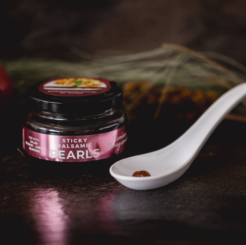 Sticky balsamic pearls jar with spoon holding dark pearls