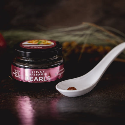 Sticky balsamic pearls jar with spoon holding dark pearls