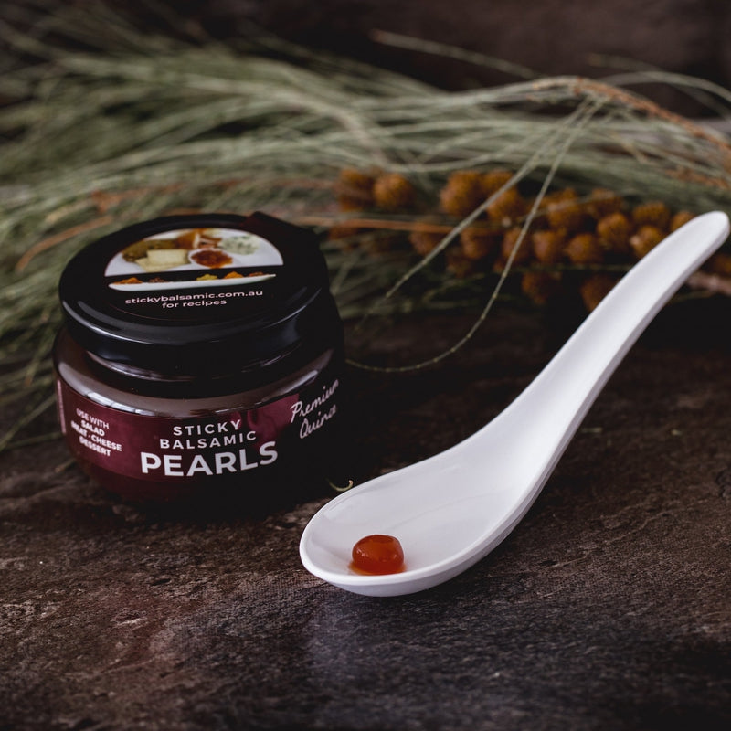 Sticky balsamic pearls jar with serving spoon and amber balsamic pearls