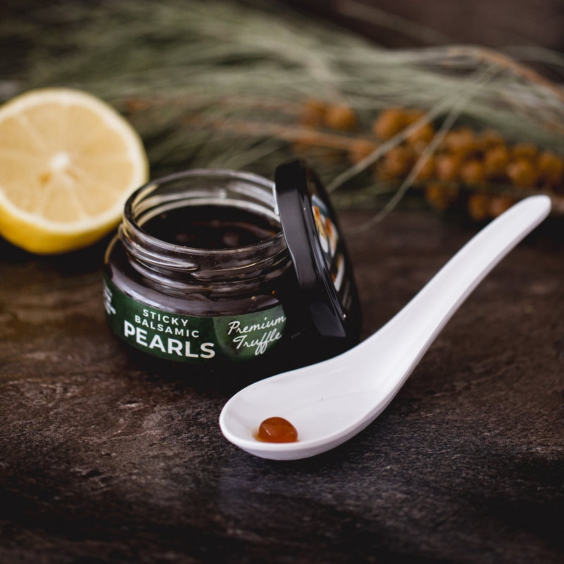 Sticky balsamic truffle pearls jar with white spoonful of dark pearls